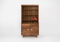 a wooden bookcase with two pink vases on top