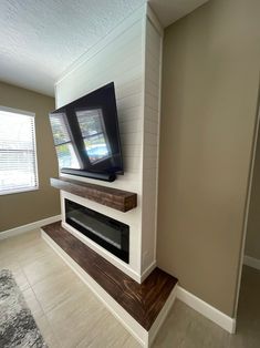 a flat screen tv sitting on top of a wooden shelf in a living room next to a window