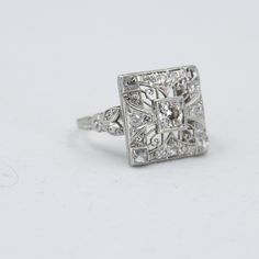 Platinum Edwardian diamond ring. Beautiful filigree and engraved square mounting. Old cut center stone .45 carat surrounded by single cuts. The corners have table cut stones . ~1.25 carat total weight. Size 7 3/4 Ring is of style that may be sized by a jeweler. 0.20 Oz total weight of ring Jewelers Appraisal available upon request. This item is vintage. It has been cherished, worn, and preserved by possibly many over the decades of its unique existence. Noted signs of age and restoration: One si Fine Jewelry Square Cut Diamond Ring For Wedding, Luxury Wedding Rings With Square Cut, Luxury Square Cut Wedding Rings, Square Cut Diamond Ring For Wedding, Luxury Square Cut Diamond Wedding Ring, Wedding Square-cut Platinum Diamond Ring, Fine Jewelry Square Cut Diamond Ring, Wedding Square Cut Platinum Diamond Ring, Square Cut Platinum Wedding Diamond Ring