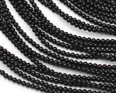 black seed beads are lined up on a white surface