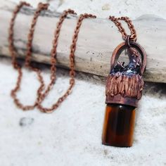 a brown bottle with a chain hanging from it's side next to a piece of wood