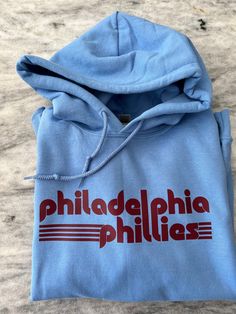 This Phillies crew comes in several color ways! Available in crew or hood. Throwback Cotton Sweatshirt With Screen Print, College Fan Apparel Crew Hoodie, College Crew Neck Fan Apparel Hoodie, College Crew Hoodie In Fan Apparel Style, Pre-shrunk Cotton Throwback Sweatshirt, Sporty Crew Hoodie For Spring, Throwback Hoodie With Letter Print And Crew Neck, Throwback Crew Neck Hoodie With Letter Print, Sporty Hoodie With Graphic Print For Baseball Season