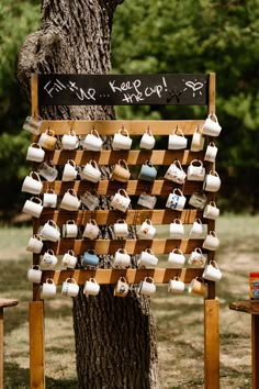 a sign with cups hanging from it next to a tree