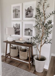 there is a tree and some pictures on the wall in this living room with two baskets