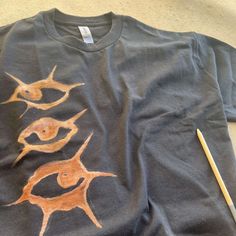 a t - shirt with an image of three fish on it and a pencil next to it