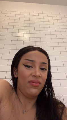 a woman is taking a selfie in front of a white brick wall and floor