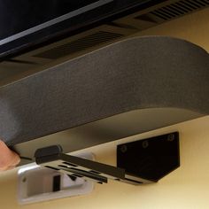 a hand is holding onto the back end of a television monitor and mounting it on a wall