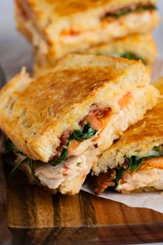 two sandwiches cut in half sitting on top of a wooden cutting board