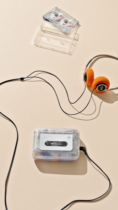 headphones and cassette tape are laying on the table next to each other, including one with an orange earbud