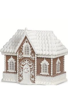 a brown and white gingerbread house with snow on the roof is sitting in front of a white background