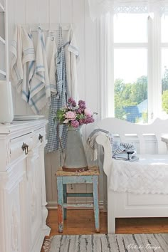 a room with white furniture and flowers in a vase