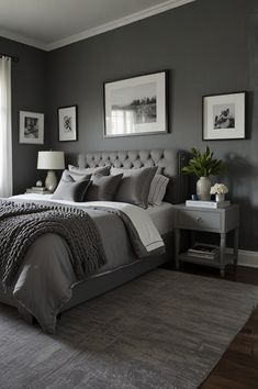 a bedroom with gray walls and grey bedding, two framed pictures on the wall