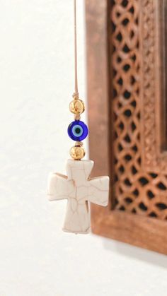 a cross with an evil eye hanging from it's side in front of a mirror