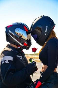 a man and woman sitting on the back of a motorcycle next to a red rose