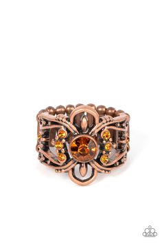 a close up of a ring with an orange stone in the center and beads around it