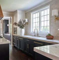 a large kitchen with marble counter tops and black cabinetry, along with an island in the middle