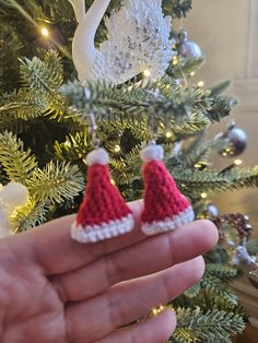 someone is holding their tiny christmas ornaments in front of the tree