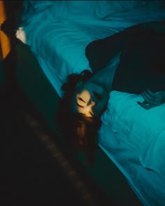 a woman laying on top of a bed in a dark room