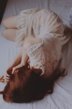 a woman laying on top of a bed with her head in her hands and the words giny above her