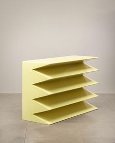 a yellow shelf sitting on top of a floor next to a white wall in an empty room