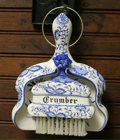 a blue and white brush with the word crumbr on it hanging from a hook