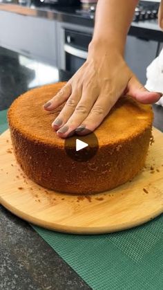 a woman is placing an item on top of a cake that is sitting on a cutting board