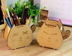 two cardboard cats sitting on top of a wooden desk next to pencils and markers