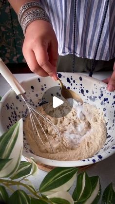 a person mixing something in a bowl with a whisk on top of it