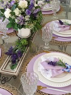 the table is set with purple and white plates, napkins, and vases