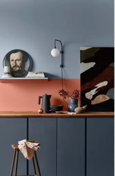 a kitchen with blue cabinets and an orange painted wall, along with a wooden bar stool