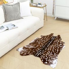 a living room with a white couch and some deer rugs on the wooden floor