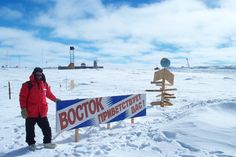 a man standing next to a sign in the snow