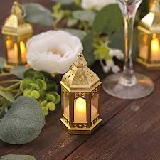 three lit candles sitting on top of a wooden table next to flowers and greenery