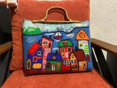 a hand painted purse sitting on top of an orange chair