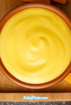 a wooden bowl filled with yellow liquid on top of a table