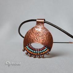 a close up of a piece of jewelry on a white surface with a black cord