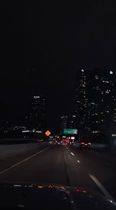 the city skyline is lit up at night as cars drive down the highway in front of them