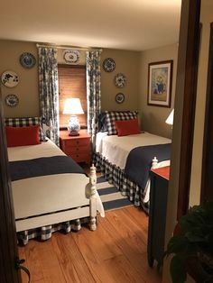 two twin beds in a bedroom with blue and white decor on the walls, along with wooden flooring