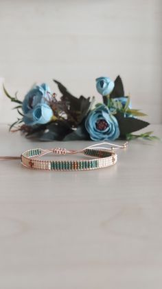 two bracelets sitting on top of a table next to flowers