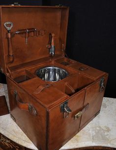 an open trunk with a metal bowl in the middle and other items around it on a table