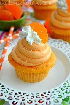 cupcakes with orange frosting and sprinkles on a plate