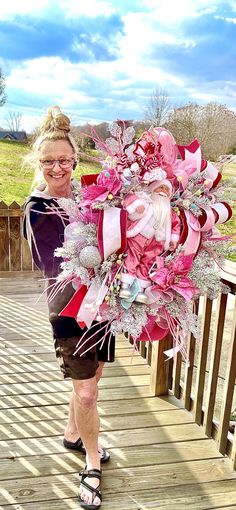 a woman standing on a wooden deck holding a bouquet of pink and white flowers in her hands