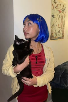 a woman with blue hair holding a black cat