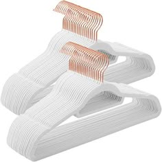 three white and orange plastic hangers on a white background with clippings attached to them