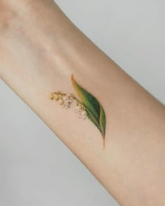 a green leaf and flower tattoo on the left arm with small white flowers around it