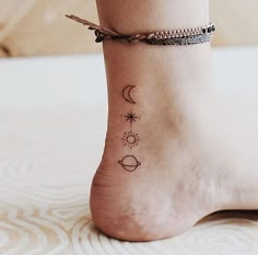 a woman's foot with two small tattoos on the side of her ankle and an arrow