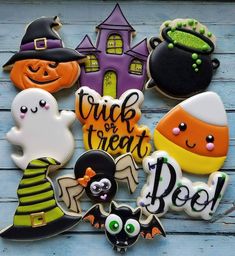 some decorated cookies are sitting on a wooden table with the words trick or treat spelled in front of them