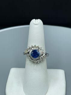 This is a beautiful 18k white gold Burma Sapphire and Diamond ring.  The vivid royal blue Burmese no heat Sapphire weighing 2.37 carat is an eye shaped gem. There are lovely clean and colorless Diamonds surrounding the Sapphire. The clarity of the diamonds are VS1 and they are H-J color. This truly unique creation would be a great addition to any fine jewelry collection or a gift for that someone special. This item is new and unworn. Gia-certified Cluster Sapphire Ring With Diamond, Gia Certified Sapphire Cluster Jewelry, Gia Certified Cluster Sapphire Ring With Diamond, Exquisite Tanzanite Round Cut Rings, Cluster Diamond Sapphire Ring, Cluster Sapphire Ring With Diamond, Fine Jewelry Sapphire Cluster Ring With Center Stone, White Gold Halo Ring With Cubic Zirconia Gemstone, Luxury Sapphire Ring With Round Stone