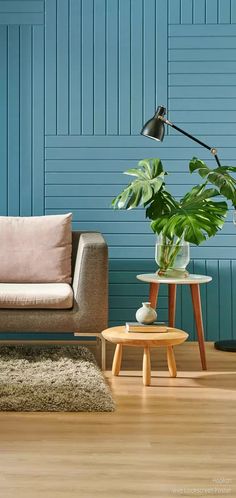 a living room with blue painted walls and wooden flooring, two small tables on either side of the couch