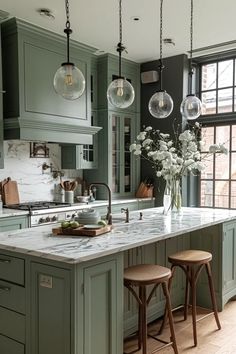 a large kitchen with green cabinets and marble counter tops, two stools are in front of the island